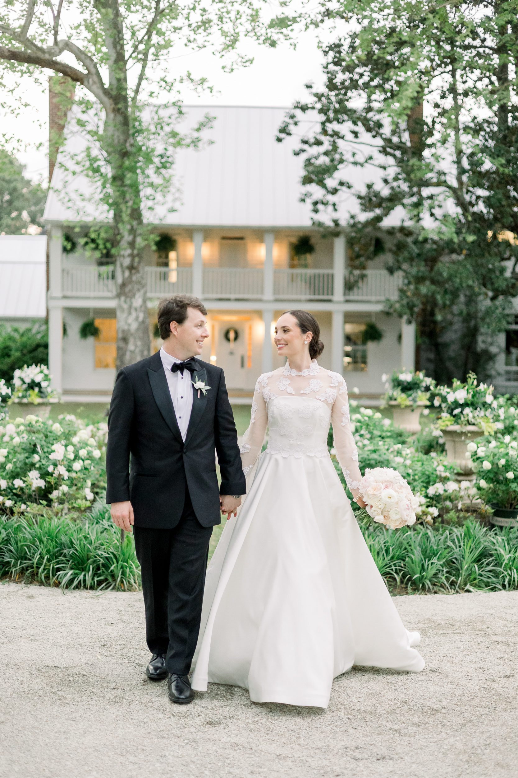 Bride and groom walking hand in hand through the gardens at Sycamore Bend Estate in Wilmington NC