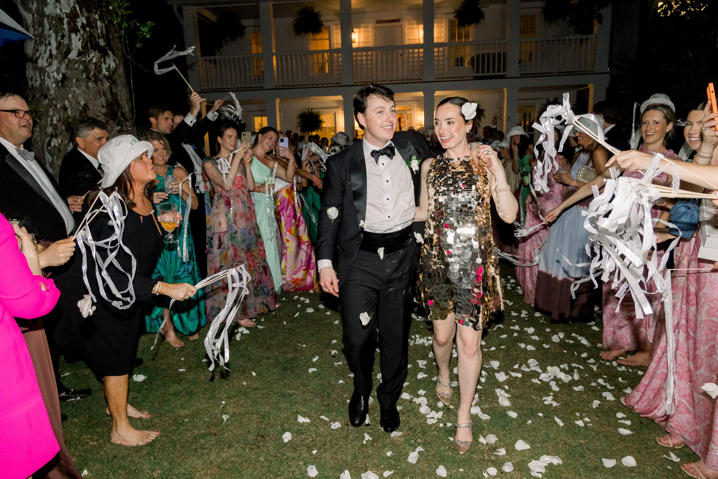 Bride and groom leaving their Sycamore Bend wedding reception in Wilmington NC surrounded by guests and glowing lights.