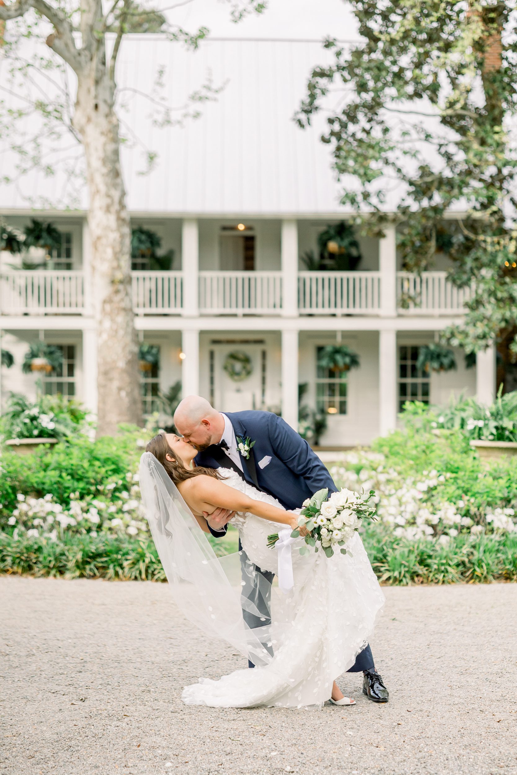 Bride and groom sharing a kiss in front of the manor house at Sycamore Bend Estate in Wilmington NC