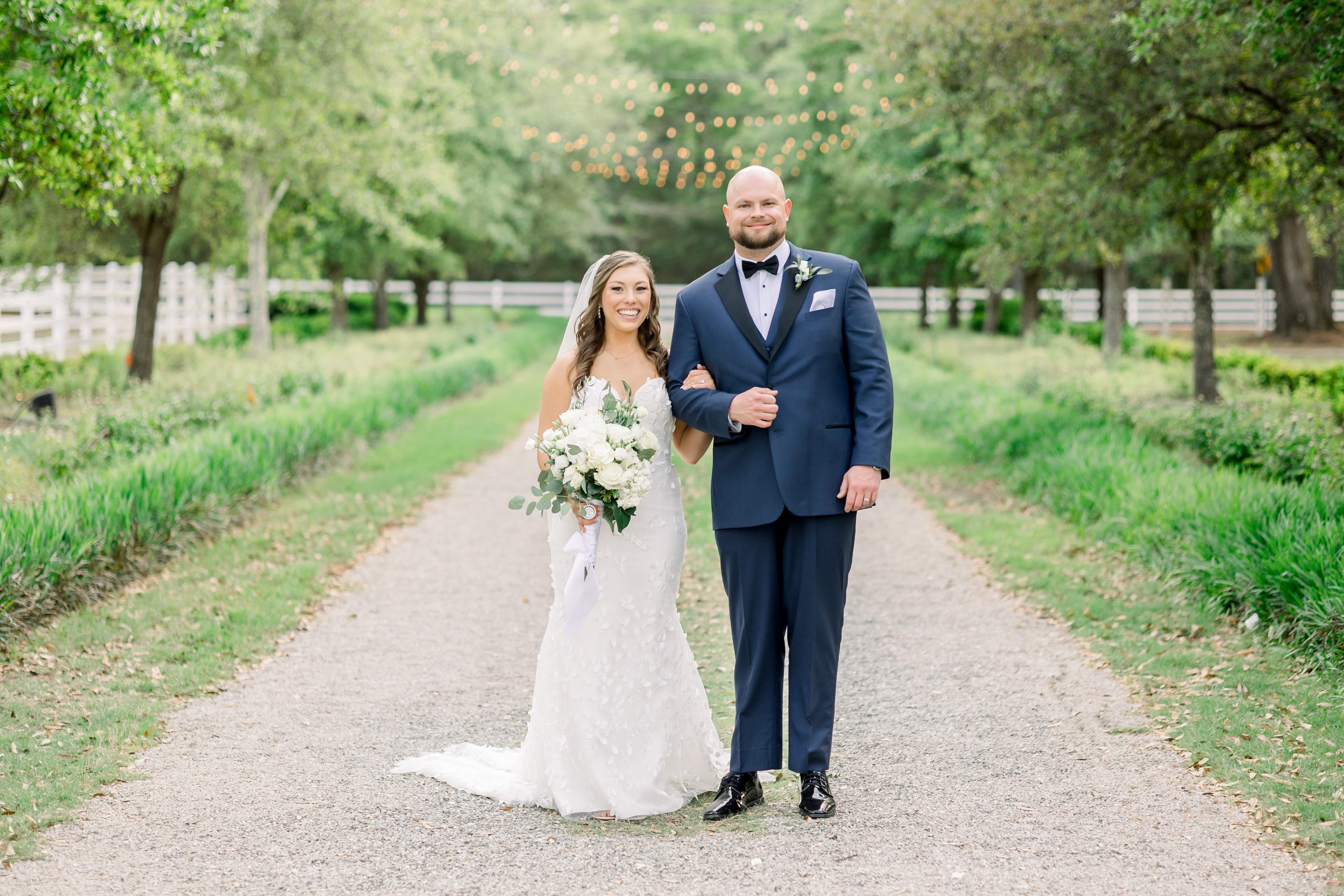 Bride and groom standing together on the grounds of Sycamore Bend Estate in Wilmington NC on a tree lined path.