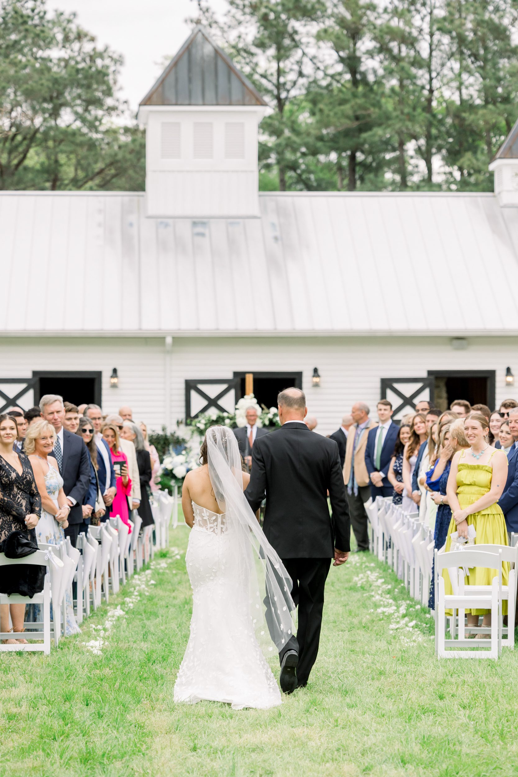 Bride walking down the aisle with her father at Sycamore Bend wedding in Wilmington NC surrounded by family and friends