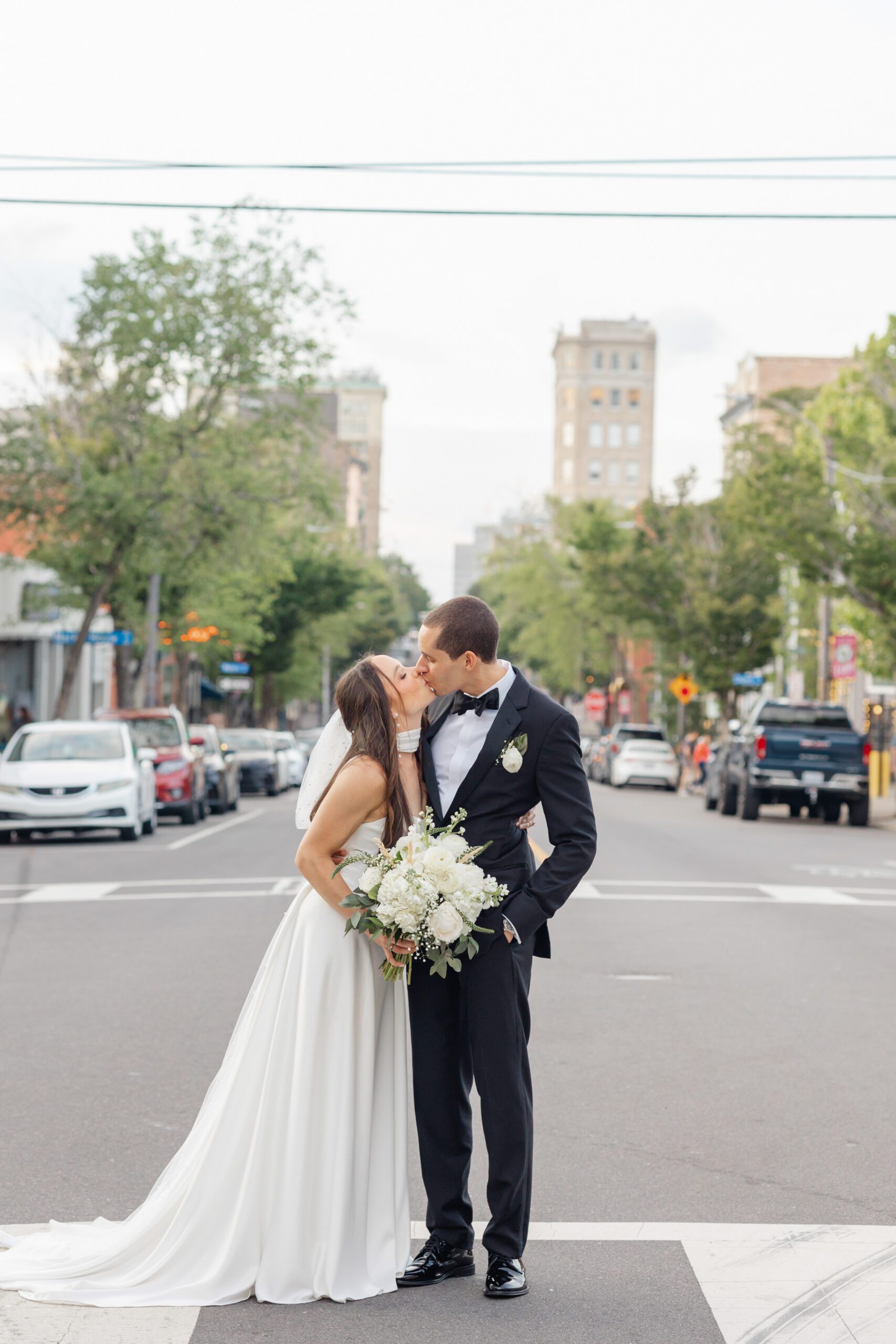 Bride and groom standing together with downtown Wilmington behind them.