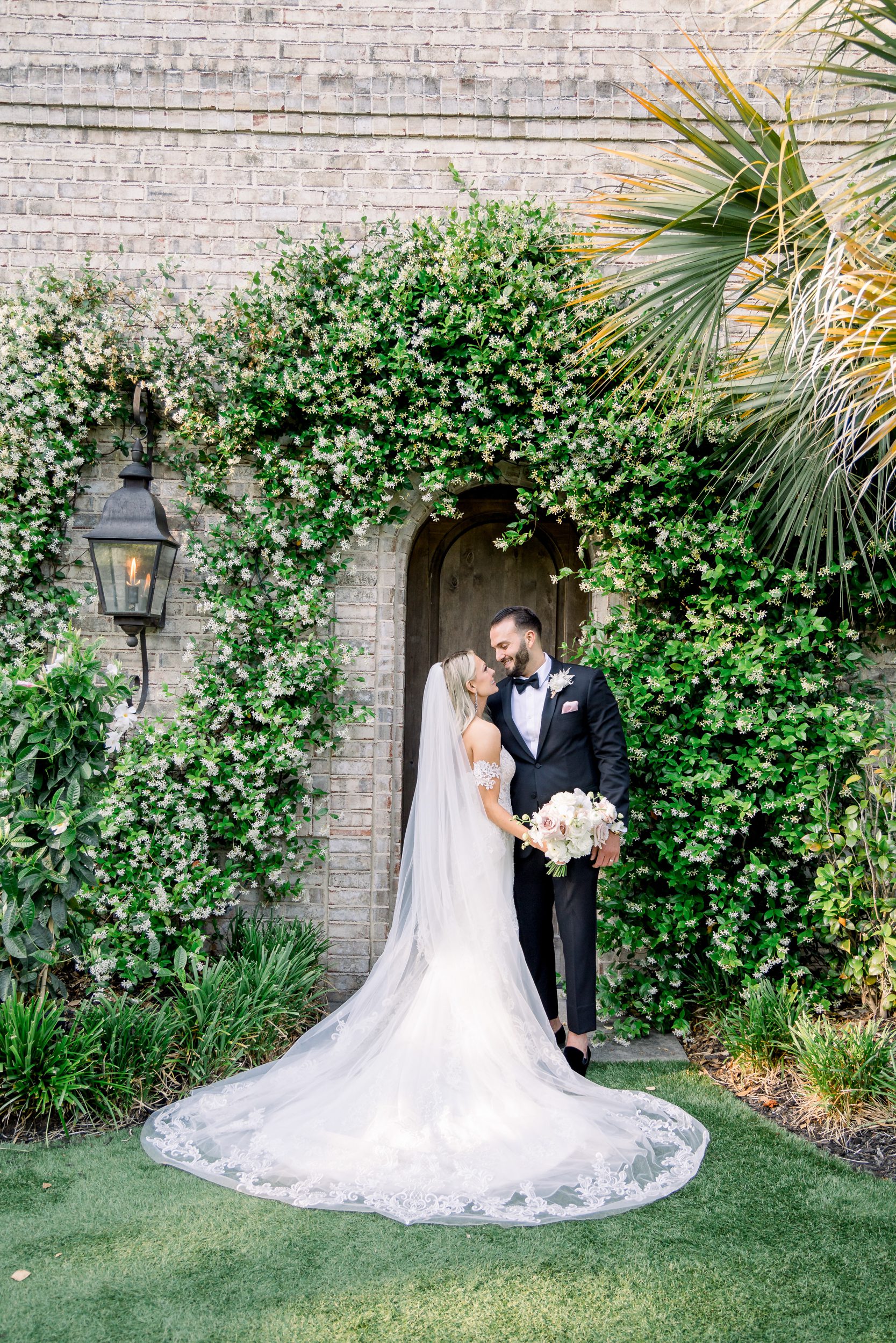 Bride and groom standing in front of the greenery-covered doorway at Wrightsville Manor in Wilmington NC