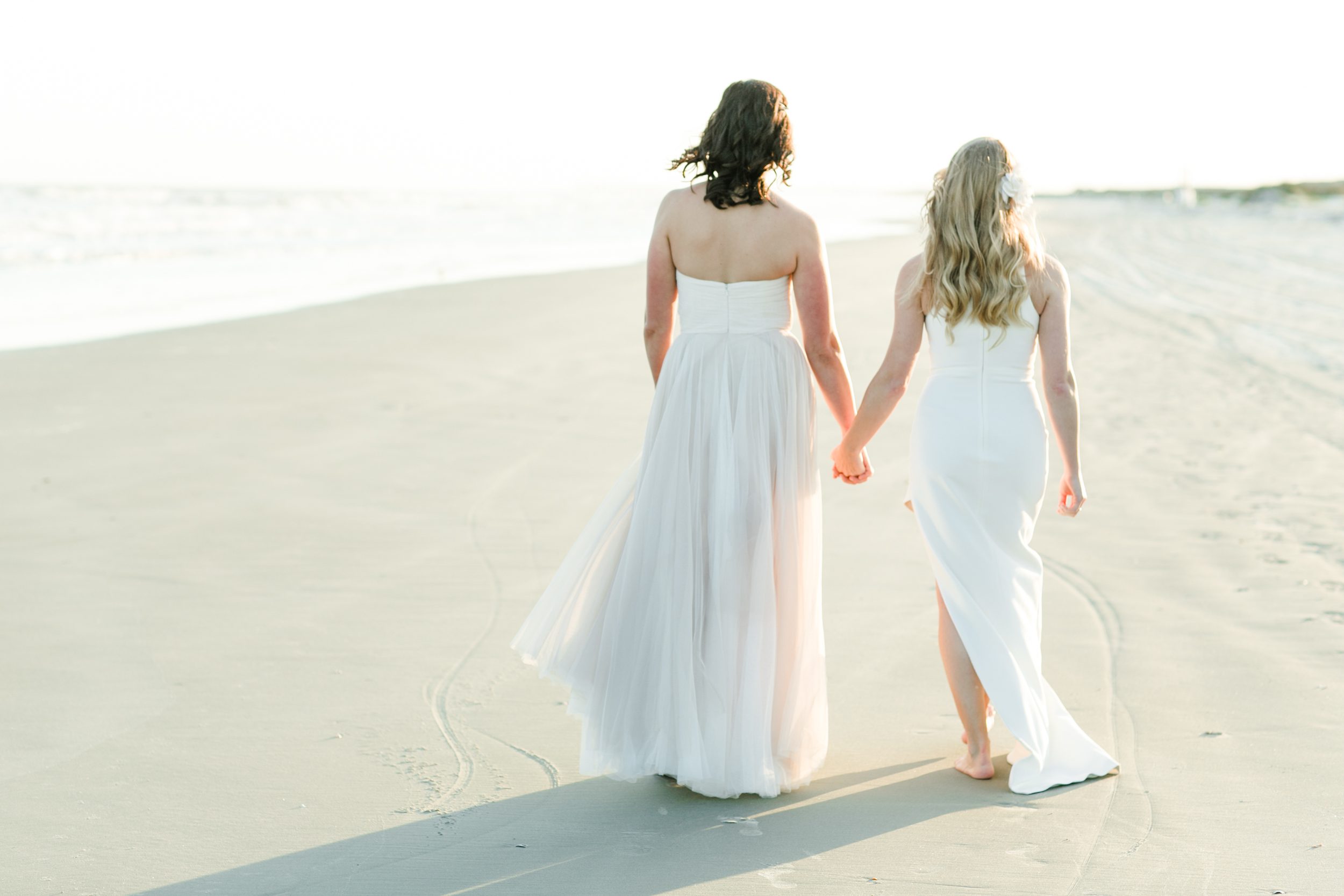 Two brides walking together on Wrightsville Beach during their wedding